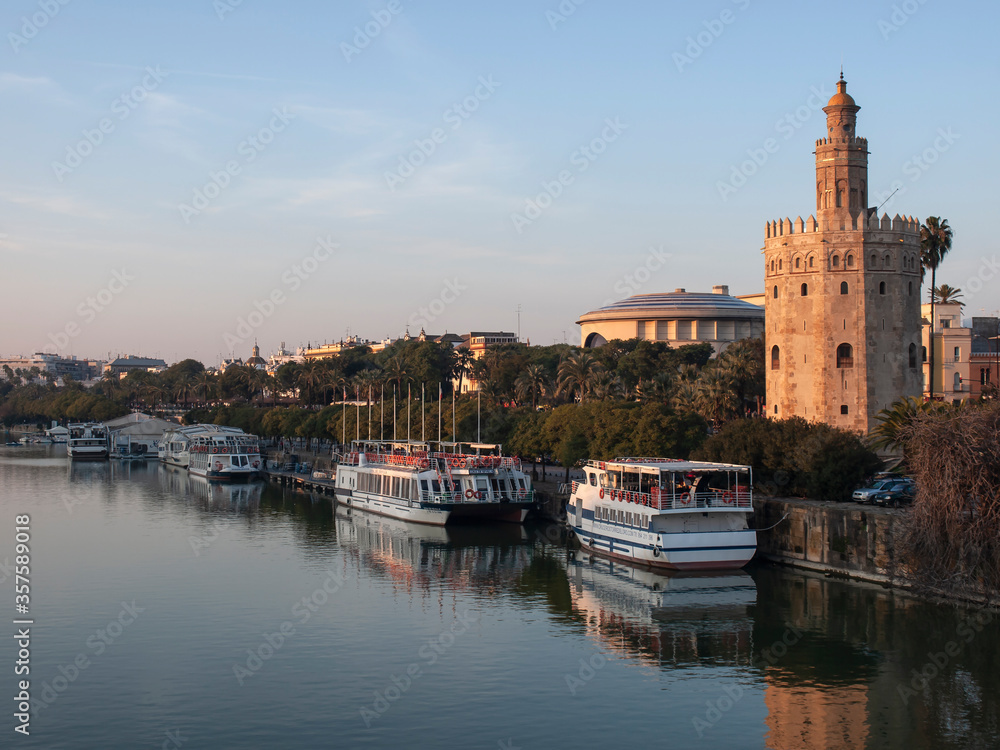 View of the Torre del Oro reflected in the Guadalquivir river and behind the Maestranza Theater, Seville, Andalusia, Spain