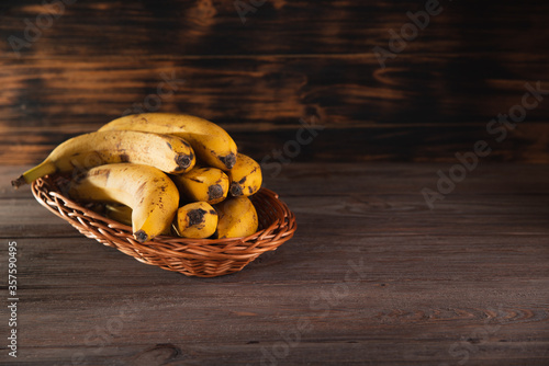 Bananas in a basket on a wooden brown natural background