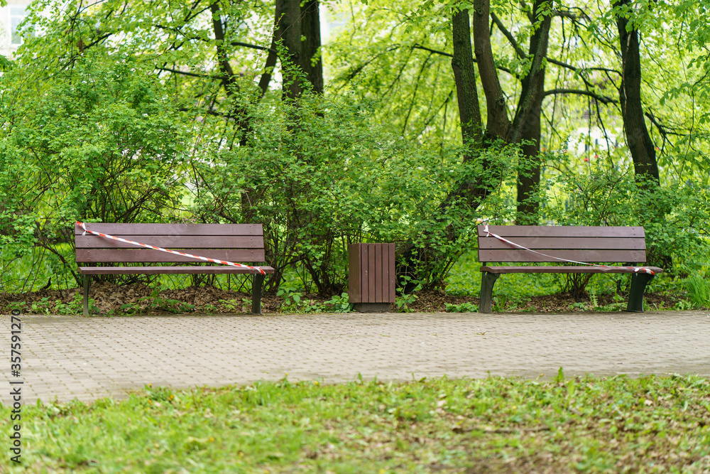 Tape fence across the bench. No people. Desert street in the spring day. Concepts - Stay at home, save live, self-isolation. Coronavirus Pandemic lifestyles Tape fence across the bench. No people. Desert street in the spring day. Concepts - Stay at home, save live, self-isolation. Coronavirus Pandemic lifestyles