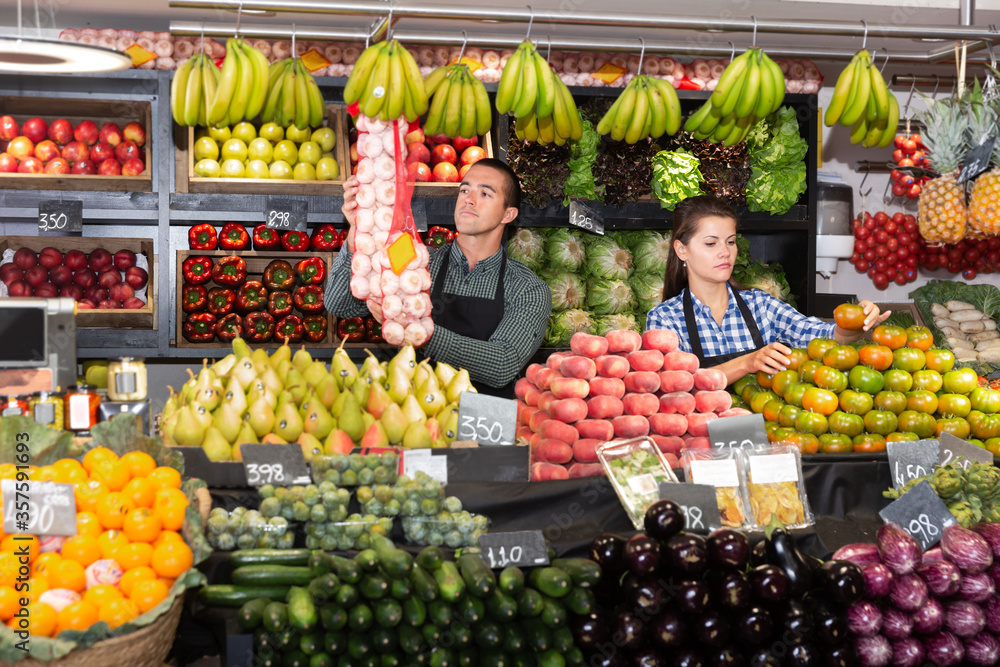 Two sellers laying out vegetables