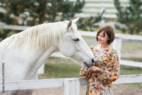 View of a beautiful women in dress with a white horse on the countryside.photo with animals.equitation.