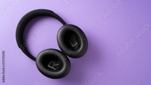 listen your music all the time. best gift for teens. black wireless headphones on purple background.