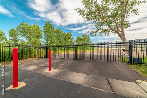 Private gate at a secured property with red traffic poles on the paved gray road