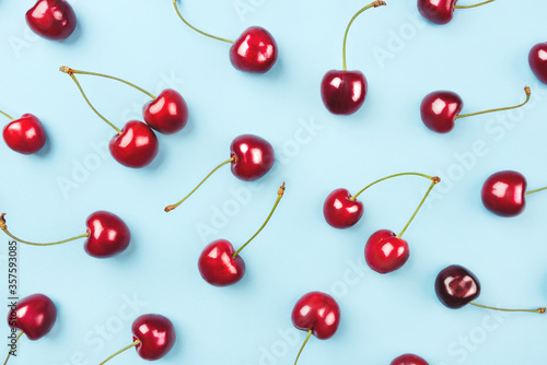 Bright pattern of ripe cherries on a blue background. Flat lay  top view.