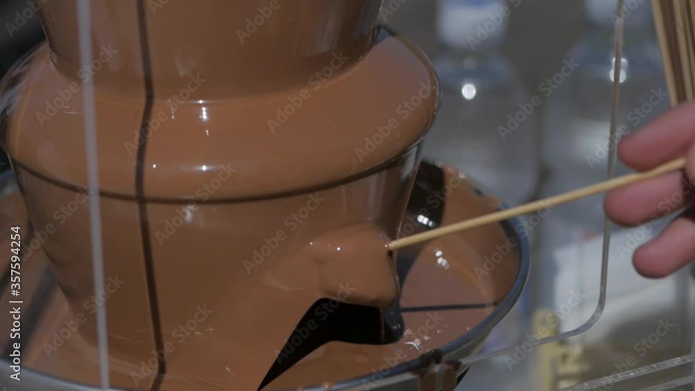 Party and celebration. People dipped banana in chocolate fountain. Celebration.Dipping a banana into a chocolate fountain.fruit in chocolate Party and celebration. People dipped banana in chocolate fountain. Celebration.Dipping a banana into a chocolate fountain.fruit in chocolate