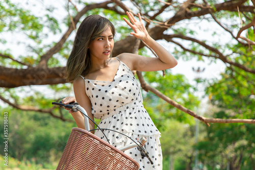 Asian woman uses her hands to protect her face from the sun.