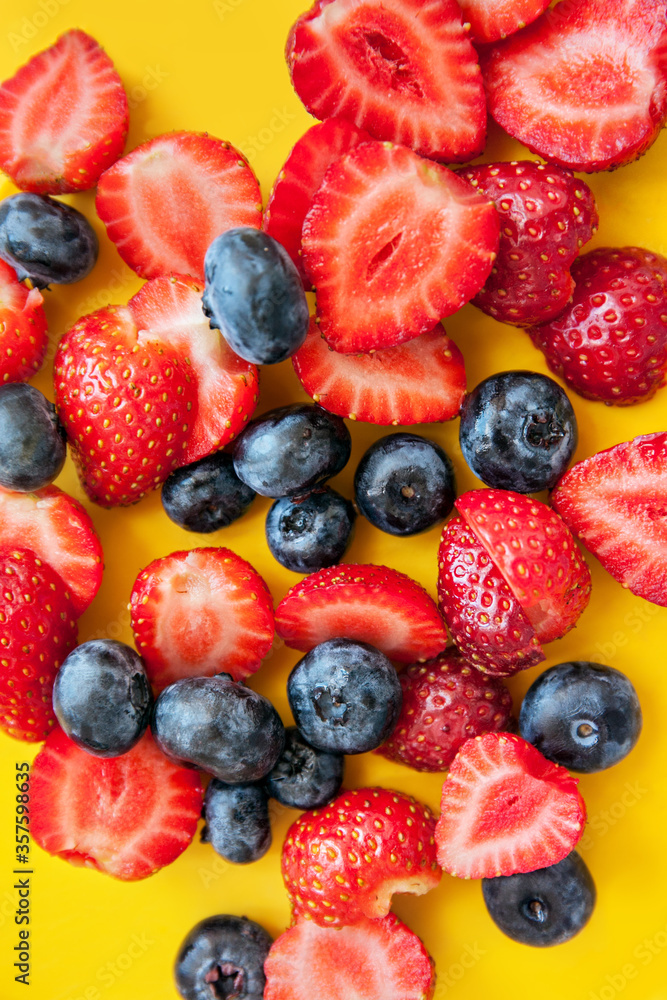Mixed fresh berries: blueberry and strawberry on a yellow background Mixed fresh berries: blueberry and strawberry on a yellow background