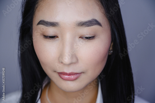 Portrait of a beautiful asian woman during eyelash extension procedure. Double eyelash volume before and after.