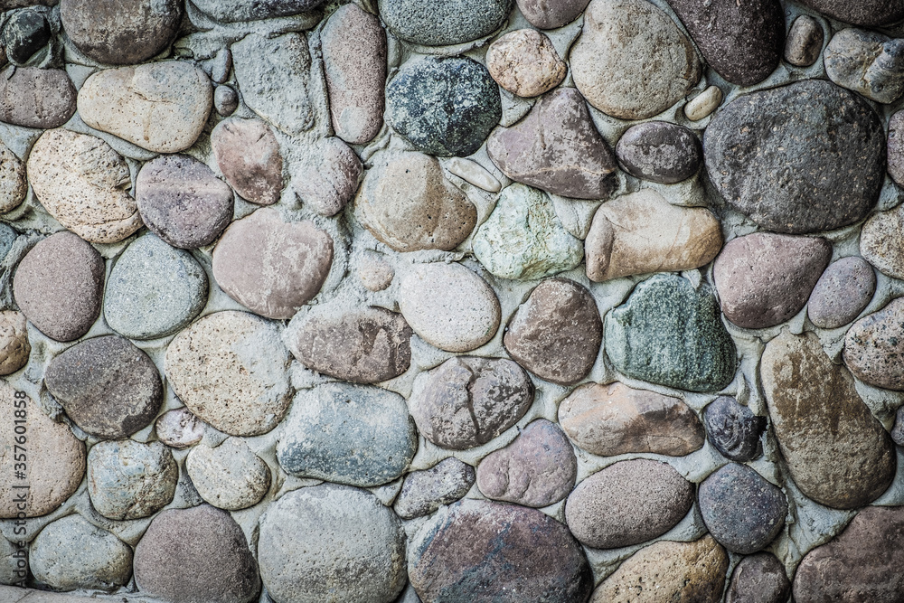 Stone wall as a background. Masonry made of natural, polished by the sea, cobblestones. Multi-colored, natural stones in the interior. Stone wall as a background. Masonry made of natural, polished by the sea, cobblestones. Multi-colored, natural stones in the interior.