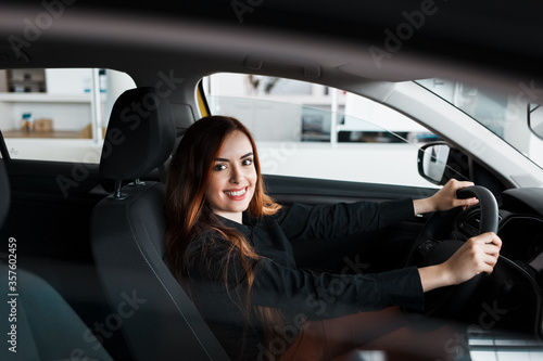 Smiling woman sitting at a car in a showroom © Andrii 
