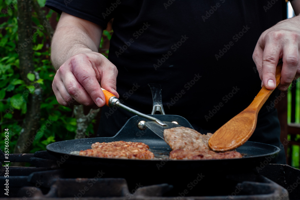 the cook roasts the cutlets in a pan over the fire. food on the grill in nature. picnic. the cook roasts the cutlets in a pan over the fire. food on the grill in nature. picnic.