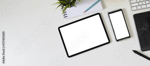Top view image of white blank screen computer tablet and smartphone are putting on a workspace.