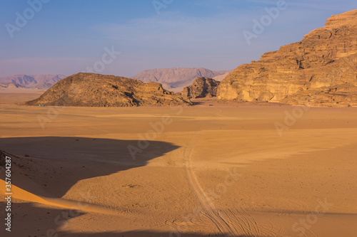 Desert with rocky mountains and wheel tracks in the sand