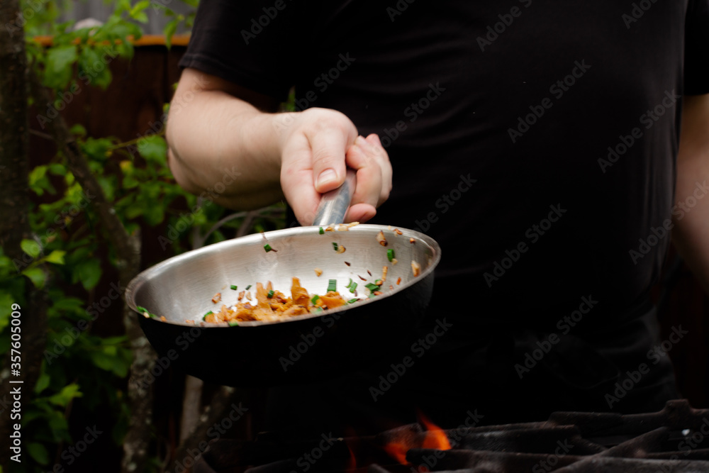 the cook roasts mushrooms with onions and herbs on the fire. chanterelles