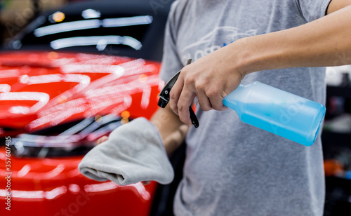 Car service worker polishing car wheels with microfiber cloth.