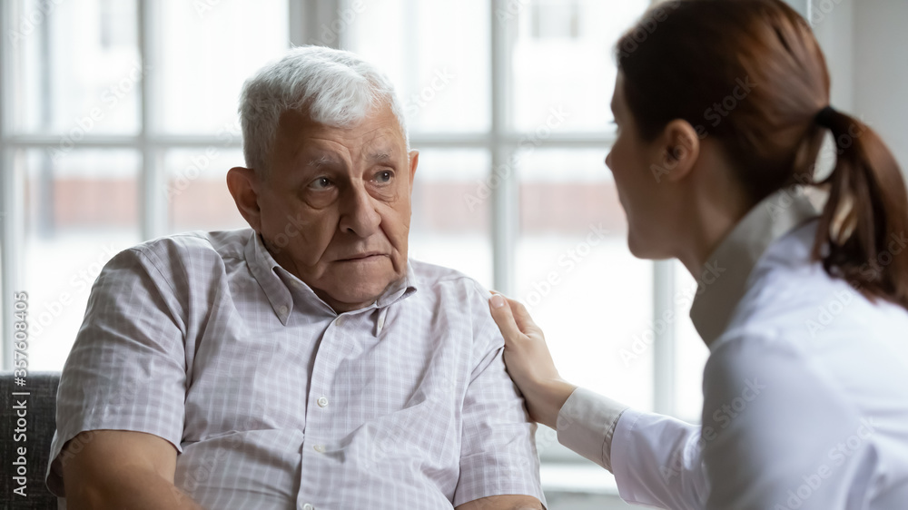 Female doctor comforting upset older patient at meeting, touching shoulder, expressing empathy and support, sad unhappy lonely mature man looking at caregiver close up, elderly healthcare concept Female doctor comforting upset older patient at meeting, touching shoulder, expressing empathy and support, sad unhappy lonely mature man looking at caregiver close up, elderly healthcare concept