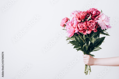 Female hand holds beautiful bouquet of peonies. Flower delivery concept © colnihko
