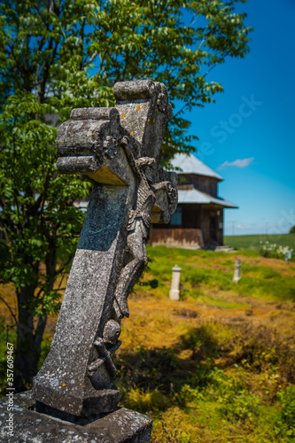 Crooked, old cross against the background of the Greek Catholic Church in Mycow.
