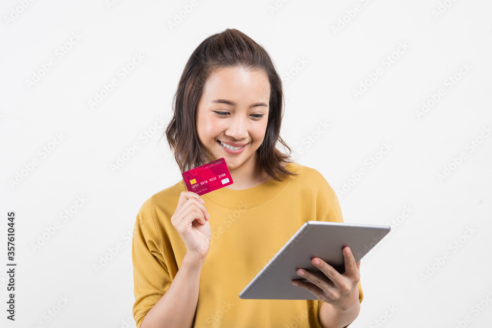 Naklejka premium young woman using her digital tablet and credit card to bring joy to the world