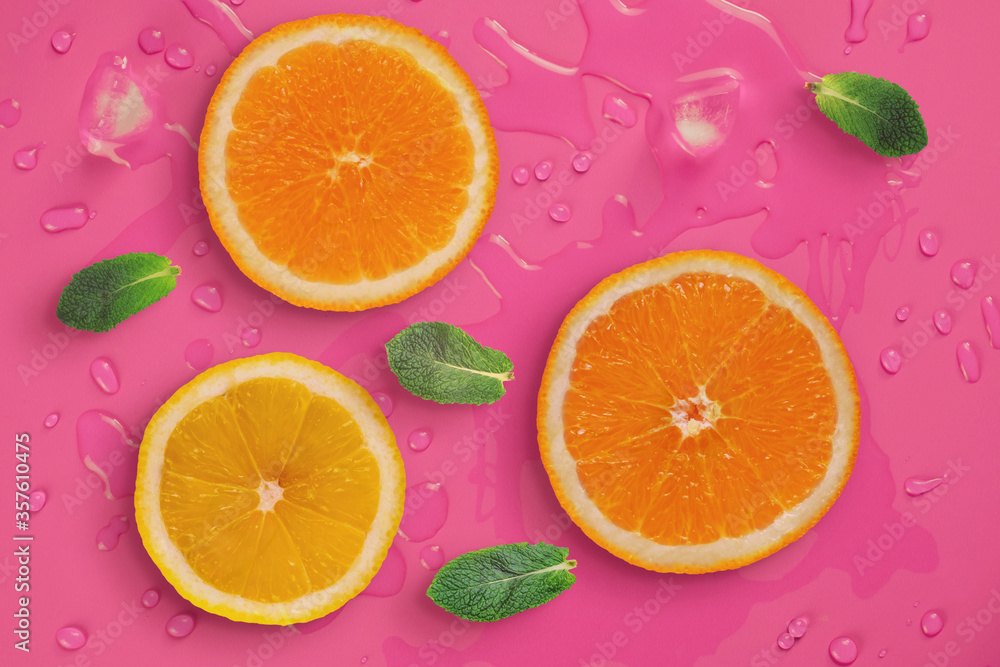 Fresh juicy slices of orange, lemon and mint leaves on bright pink background covered with water drops. Creative food background Fresh juicy slices of orange, lemon and mint leaves on bright pink background covered with water drops. Creative food background
