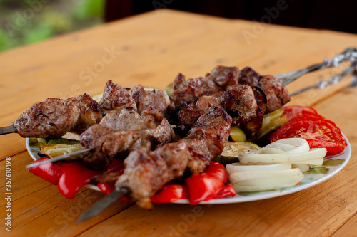 a tray with meat on skewers sprinkled with herbs on grilled vegetables