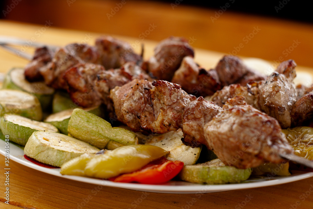 a tray with meat on skewers sprinkled with herbs on grilled vegetables a tray with meat on skewers sprinkled with herbs on grilled vegetables