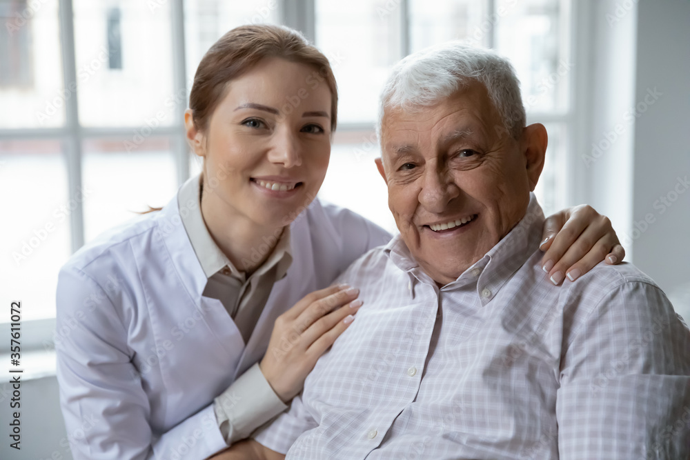 Head shot portrait smiling female doctor wearing uniform and older patient looking at camera, caring woman caregiver touching mature senior man shoulders, elderly generation healthcare concept Head shot portrait smiling female doctor wearing uniform and older patient looking at camera, caring woman caregiver touching mature senior man shoulders, elderly generation healthcare concept