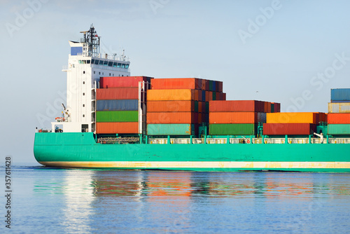 Large cargo container ship sailing from Europoort (Rotterdam, Netherlands) in an open sea on a clear day, close-up. Freight transportation, global communications, logistics, environmental damage theme photo