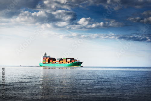 Large cargo container ship sailing from Europoort (Rotterdam, Netherlands) in an open sea on a clear day, close-up. Freight transportation, global communications, logistics, environmental damage theme photo