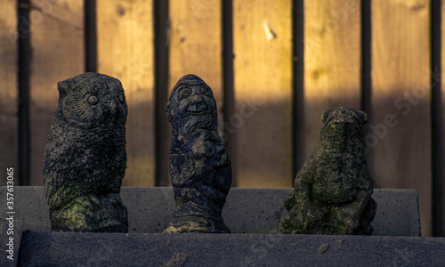 Stone Figures In Front Of Wooden Fence In England