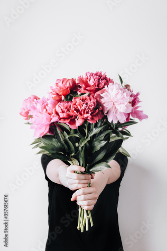 Foto Faceless girl holds a bouquet of peonies on concrete wall background