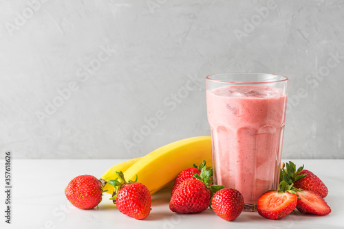 Obraz na płótnie Glass of strawberry and banana smoothie or milkshake with fresh fruits and berries