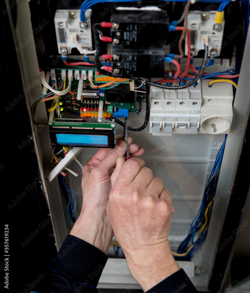The man is repairing the switchboard voltage with automatic switches.