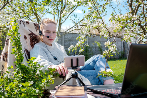 Remote work and at home in the garden. The girl works on a laptop in the garden conference, a meeting virtual communication in quarantine, lockdown covid 19.remotely work