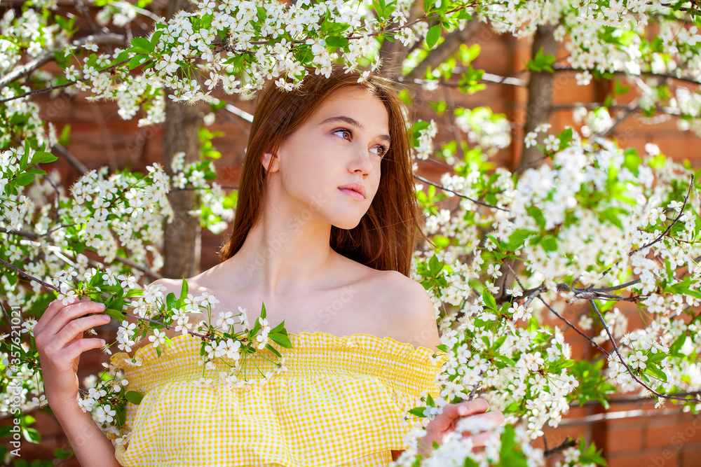 Young red-haired woman posing against the backdrop of a blossoming apple tree Young red-haired woman posing against the backdrop of a blossoming apple tree
