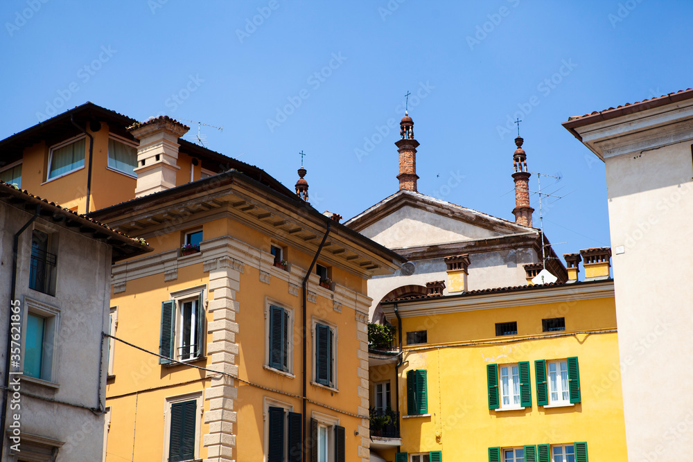 Close up. Traditional Italian old buildings in the historical center of Brescia, Lombardy, Italy. Colorful European architecture with tiled roofs, arches, wooden shutters and chimneys.