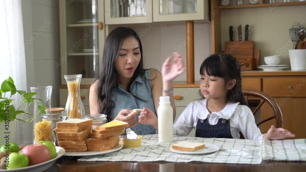 asian mother and daughter making breakfast together on the kitchen table at home in the morning asian mother and daughter making breakfast together on the kitchen table at home in the morning