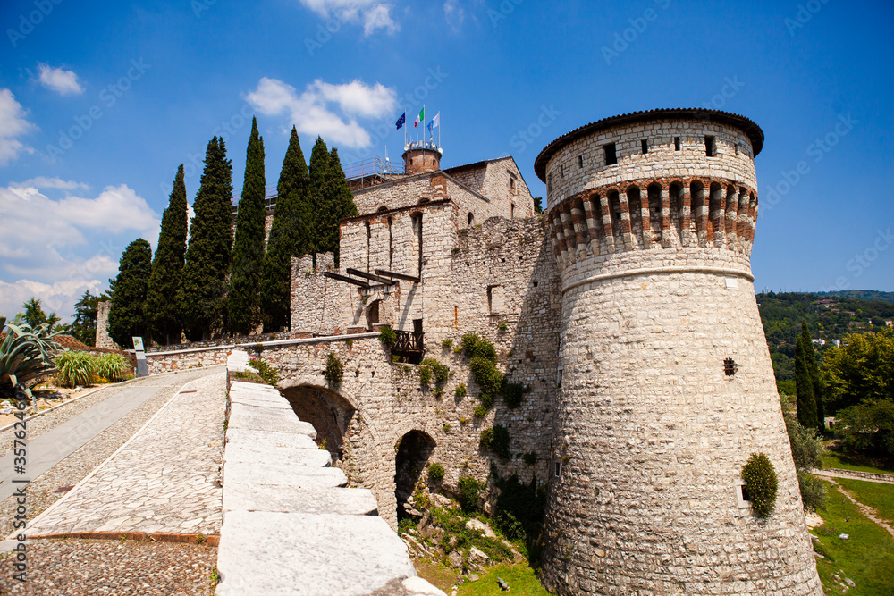 A medieval fortress (castle) with watchtowers, a trench and a walk-in bridge in front of the entrance made of white stones (bricks) in the center of the Italian city of Brescia (Lombardy, Italy).