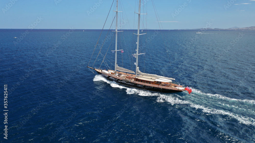 Fototapeta premium Aerial drone photo of beautiful sail boat with wooden deck sailing the Aegean deep blue sea, Greece