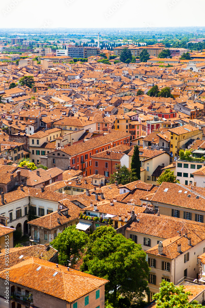 Aerial view of the historical center of Brescia (Lombardy, Italy) with tiled red roofs, chimneys, cathedral's domes and tall white brick old towers. Traditional European medieval architecture. Aerial view of the historical center of Brescia (Lombardy, Italy) with tiled red roofs, chimneys, cathedral's domes and tall white brick old towers. Traditional European medieval architecture.