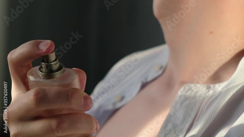 Unrecognizable man uses a perfume to apply it on the skin, close-up photo