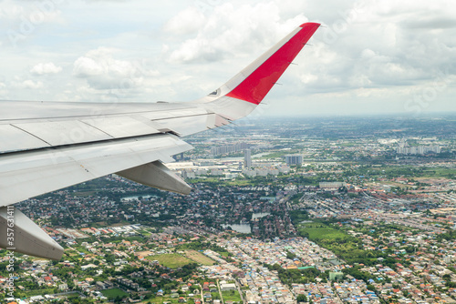 Closeup wing of airplane while flying in the air with cityscape below