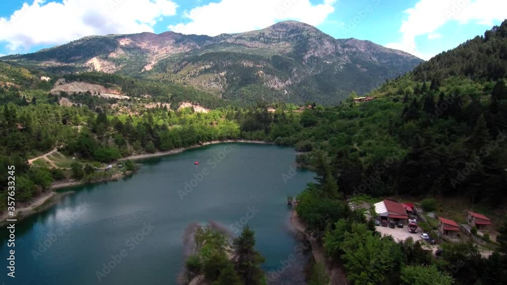 Sliding left aerial shot of lake Tsivlou view from above with green mountains surrounding peacefully the natural waters Sliding left aerial shot of lake Tsivlou view from above with green mountains surrounding peacefully the natural waters
