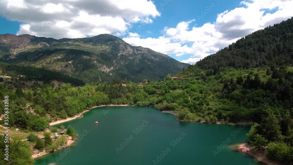 Dolly out epic reveal shot of Lake Tsivlou on an overcast cloudy day. Green natural waters surrounded by mountains Dolly out epic reveal shot of Lake Tsivlou on an overcast cloudy day. Green natural waters surrounded by mountains