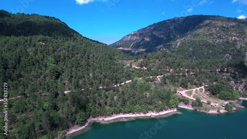 Tilt down aerial reveal shot of lake Tsivlou shore surrounded by mountains with green pine trees photo