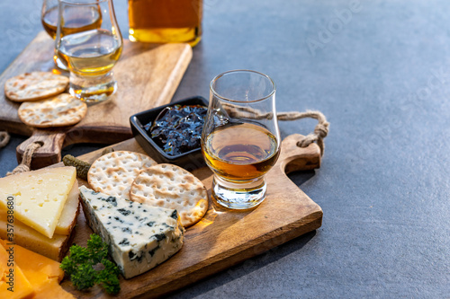 Whiskey and cheese pairing, tasting whisky glasses and plate with sliced cheeses photo