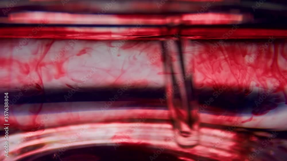 Macro of test tube with blood. Stirring red liquid in glassware with pipette Macro of test tube with blood. Stirring red liquid in glassware with pipette