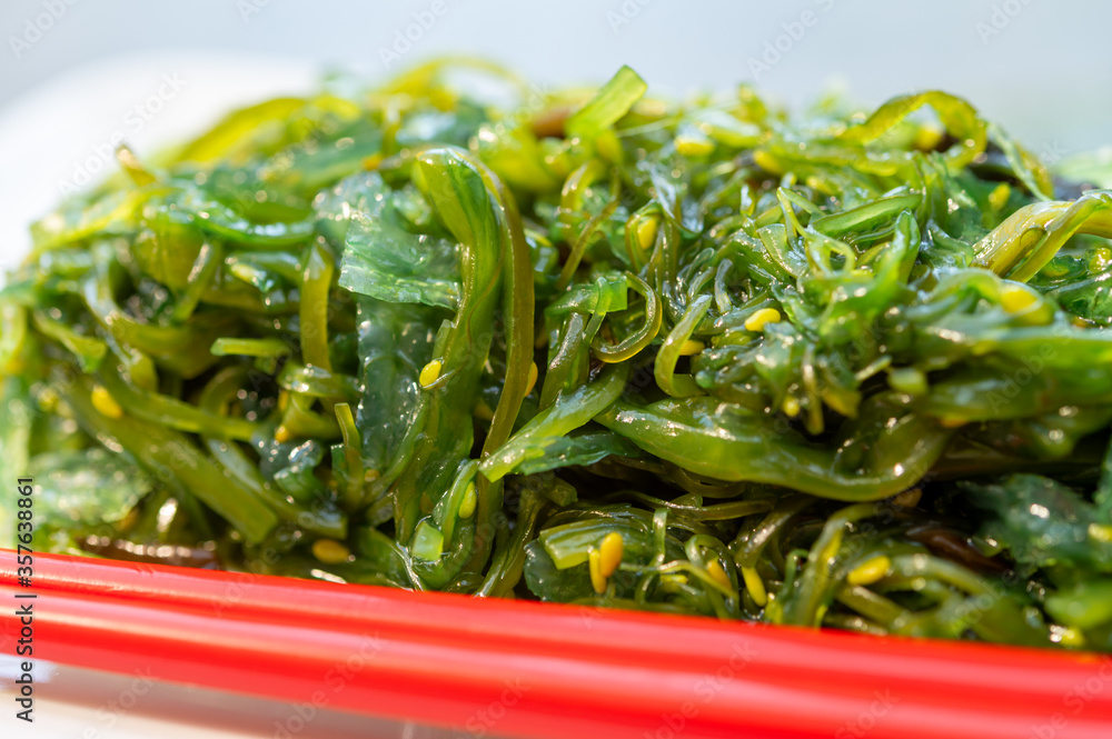 Green fresh oriental seaweed salad served with chopsticks Green fresh oriental seaweed salad served with chopsticks