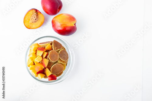 Glass bowl with tiny pancakes and slices of fruit. Fashionable food concept. Top view or flat lay.