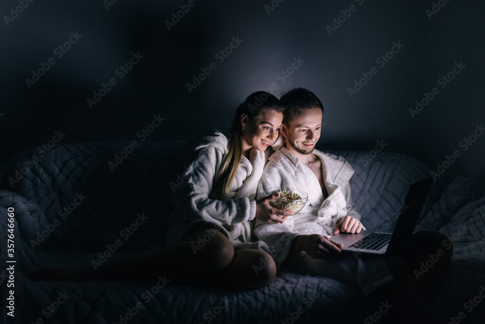 Young couple eating popcorn while watching a movie in dark room Young couple eating popcorn while watching a movie in dark room